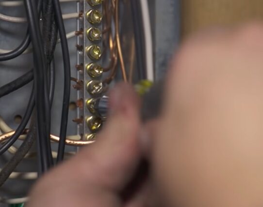 A person is working on an electrical panel with wires