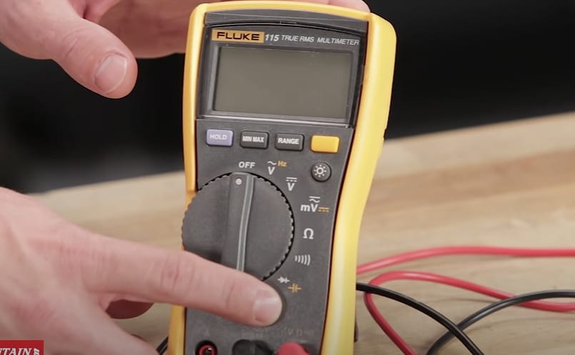 A person is holding a FLUKE multimeter