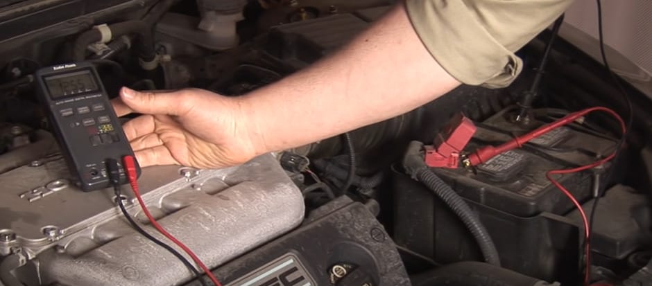 A person is using a multimeter to test the battery of a car