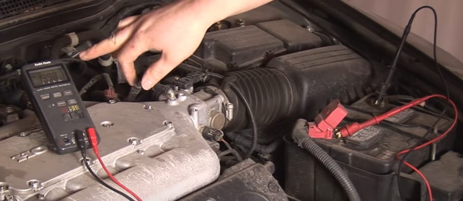 A person is using a multimeter to check the voltage of the battery in a car