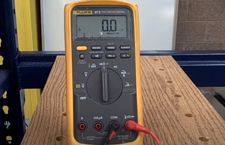 A fluke multimeter sitting on top of a wooden table