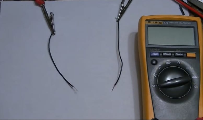 Two black wires and a multimeter in a white table