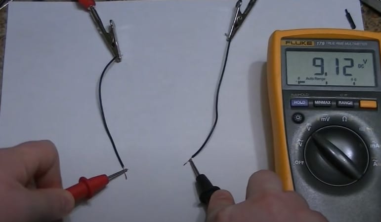A person is using a multimeter to test a wire