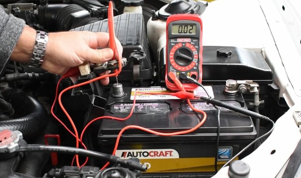 A man is using a multimeter to check the battery in a car for any signs of drain