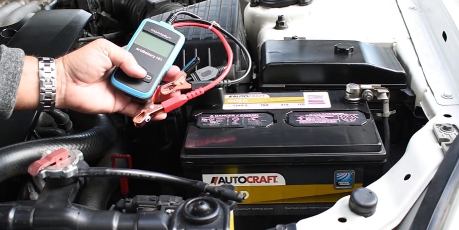 A person is using a multimeter to check for battery drain in a car