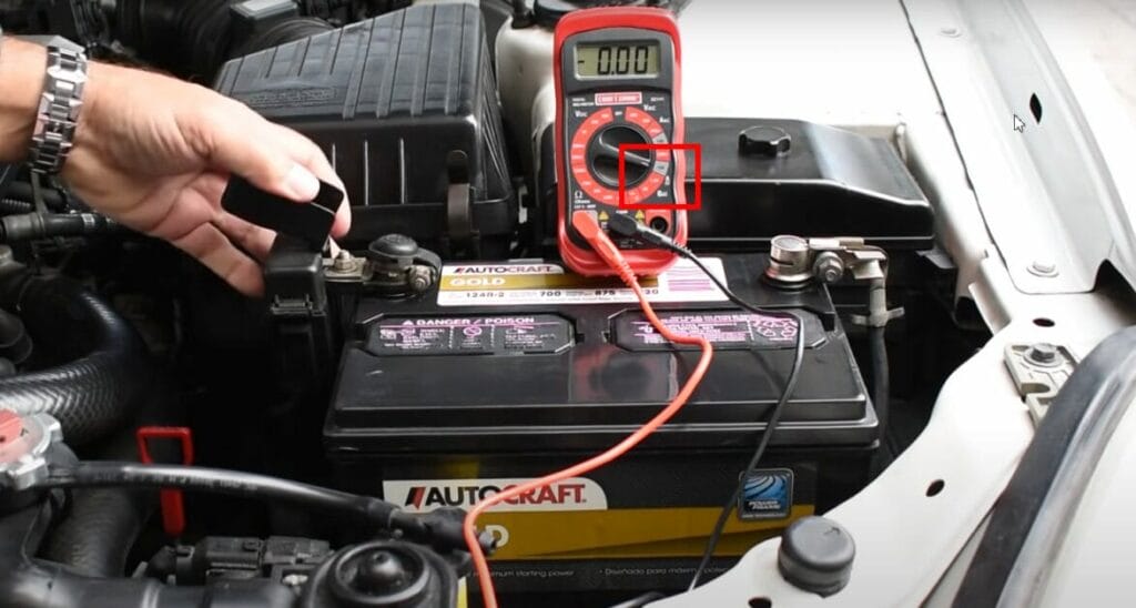 A person is using a multimeter to check the battery in a car for potential drain