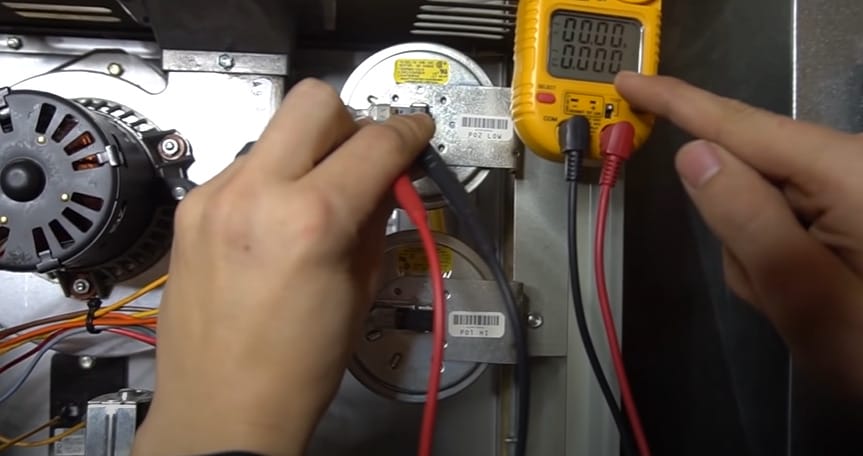 A person is working on an air conditioning unit and learning how to test a pressure switch