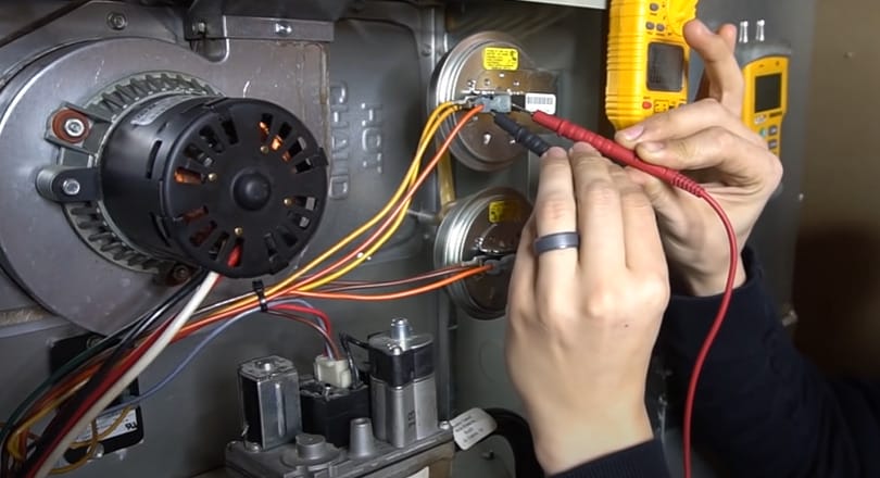 A person is testing a gas furnace pressure switch