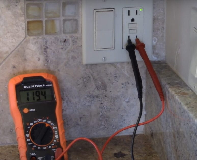 A multimeter is used to test a GFCI outlet by being plugged into a wall outlet