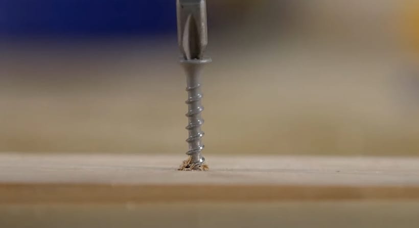 A drill bit is being drilled into a piece of wood