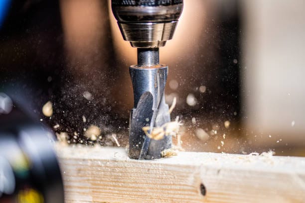 A drill bit is being used to drill a piece of wood