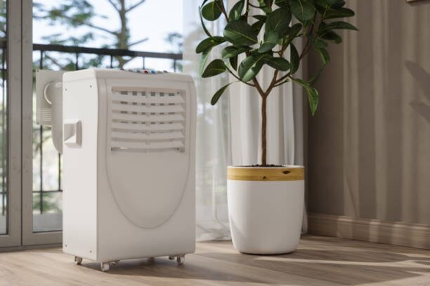 A white portable air conditioner efficiently cooling a room by a window