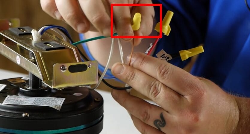 The person is putting wires, including the blue wire, into a motor