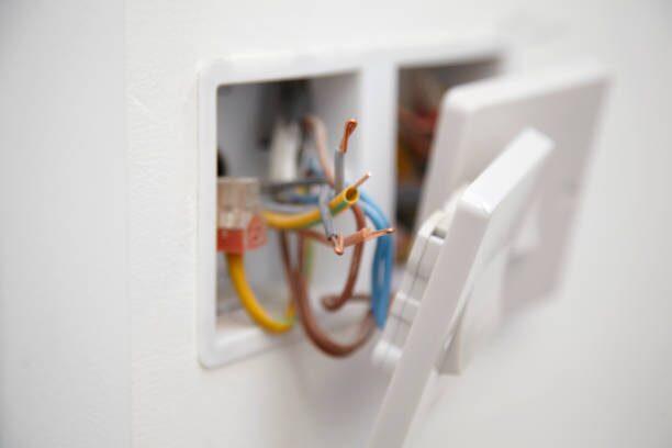 A white wall socket with wires attached to it