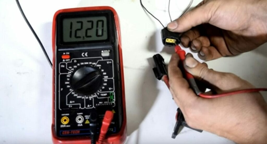 A person is attaching the multimeter’s red probe to the reference wire