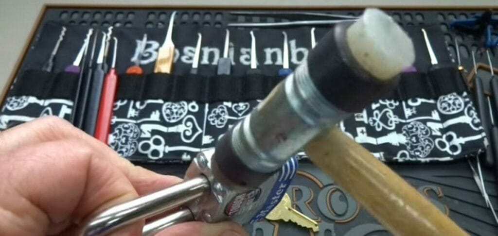 A person is using a hammer to open the metal lock