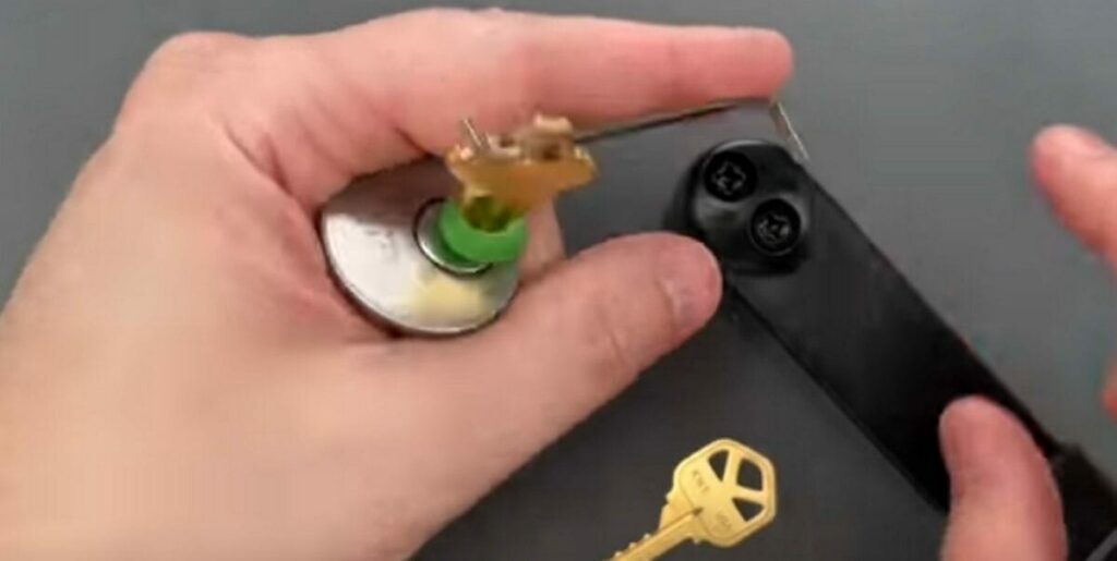 A person is putting a small tension wrench in the key’s bow