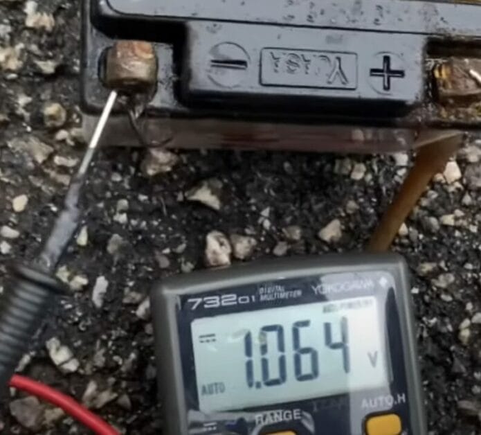 A 12v battery being tested using a multimeter