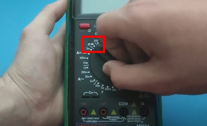 A person setting up a multimeter before testing