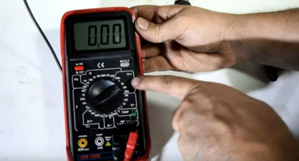 A person turning the multimeter to a low DC setting