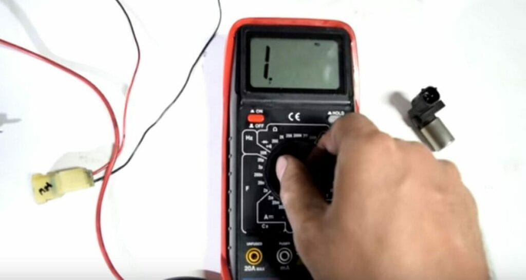 A person setting the multimeter to ohms 