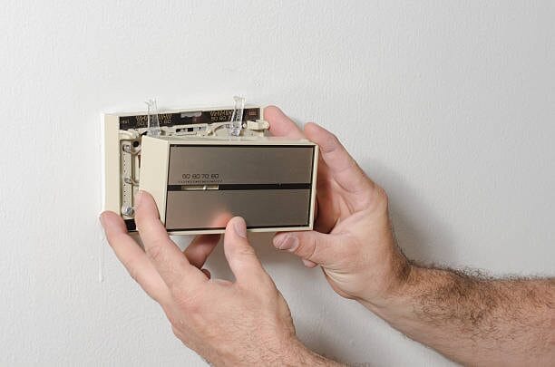 A man is holding a mercury thermostat