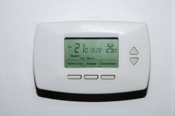 A digital thermostat on a white wall