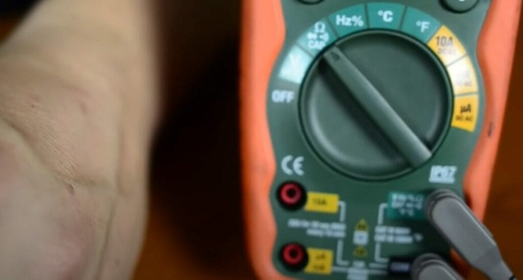 A zoom in image of a multimeter held by a person's hand