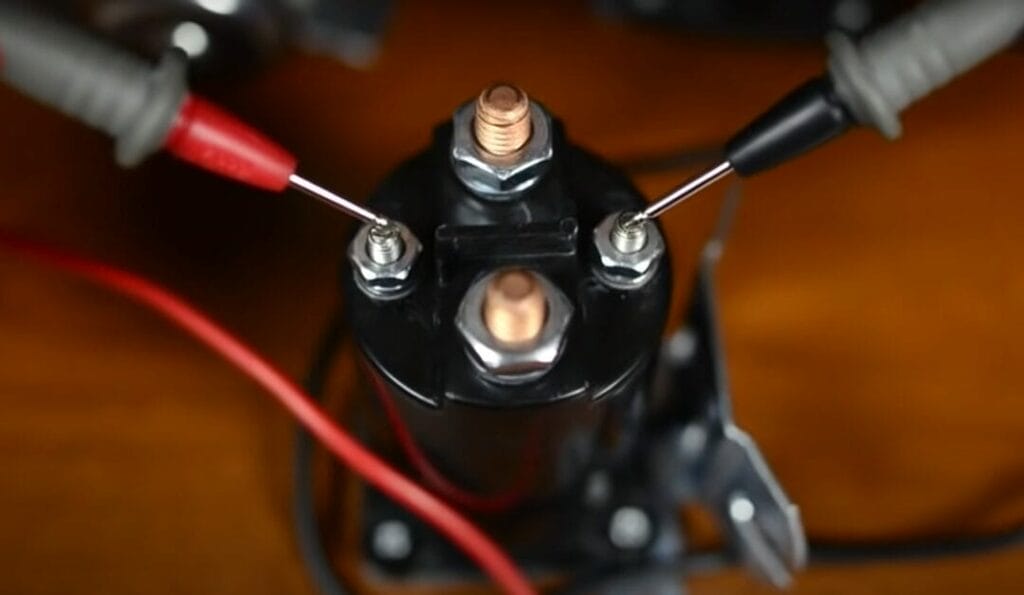 A close up of a battery with multimeter probe attached to it