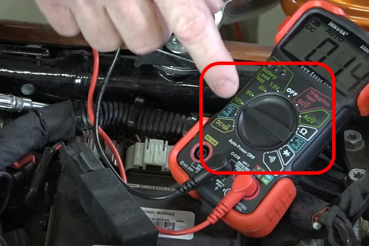 A person is putting a multimeter on a motorcycle engine to check the voltage