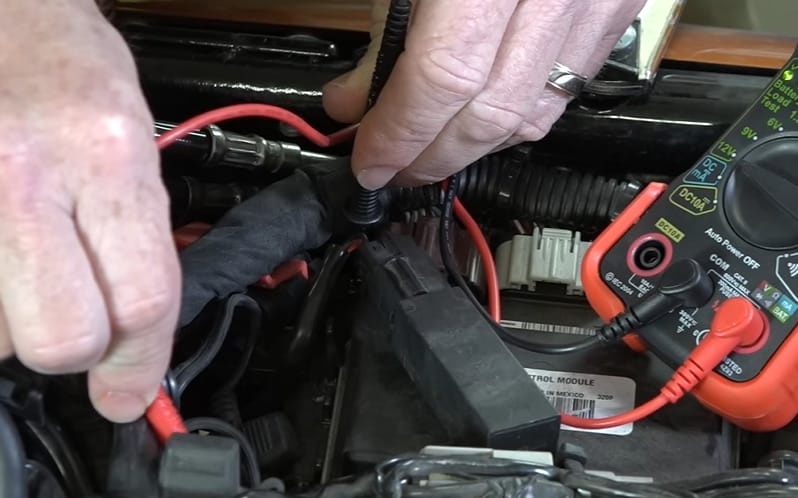 A person is using a multimeter to check the voltage of a motorcycle battery