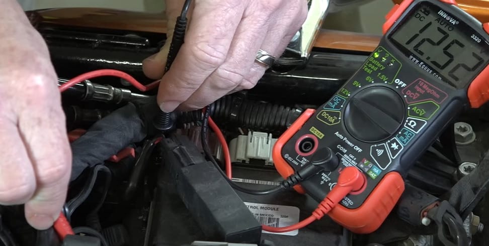 A person using a multimeter to check the voltage of a motorcycle battery