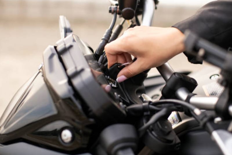 A woman's hand putting the key at the keyhole of a motorcycle