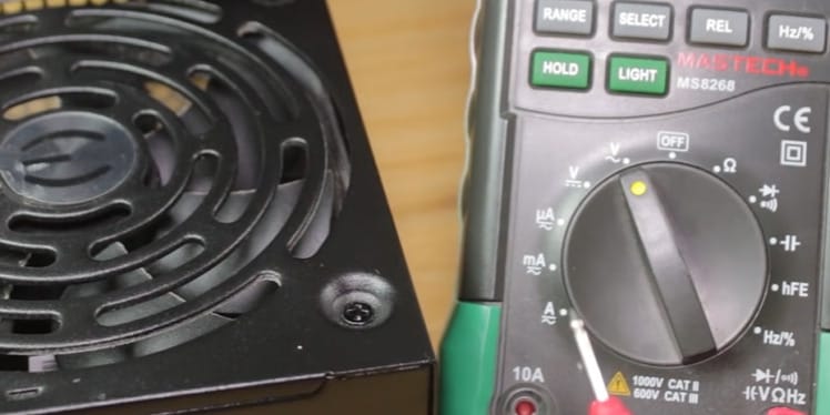 A power supply with a fan next to it that can be tested using a multimeter