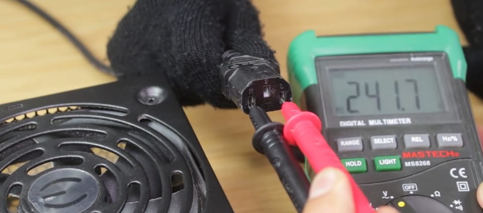 A person is using a multimeter to test a CPU fan