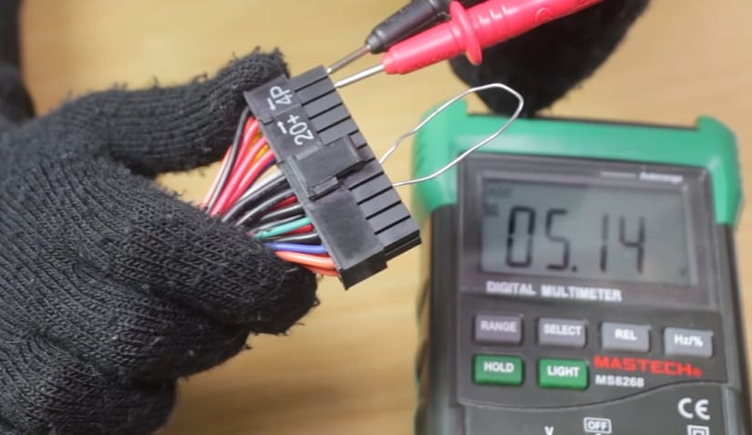 A person demonstrating how to test a 24-pin connector with a multimeter
