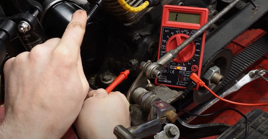 A person using a multimeter to test the stator on a motorcycle