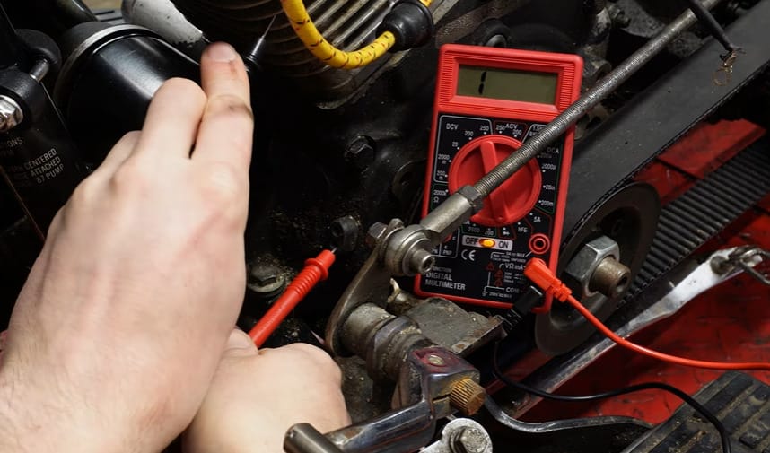 A person using a multimeter to test the stator on a motorcycle engine