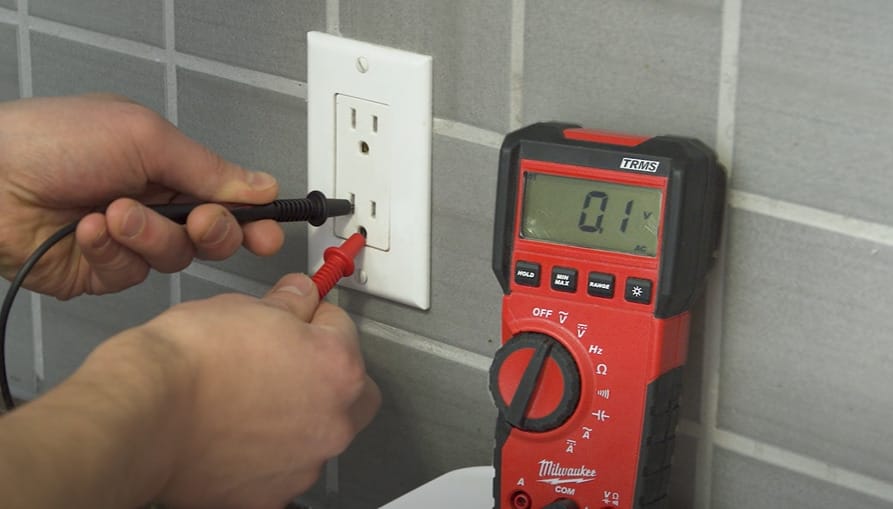 A person demonstrates how to test an outlet using a multimeter