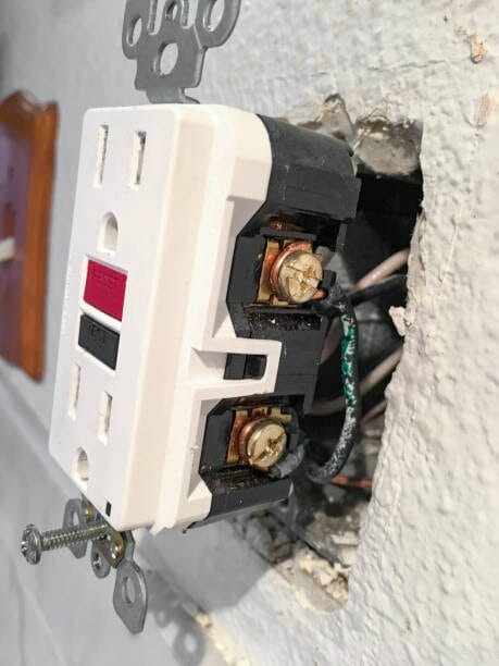 An undone white outlet with wires attached to it