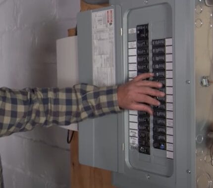A man is switching of a breaker in an electrical panel