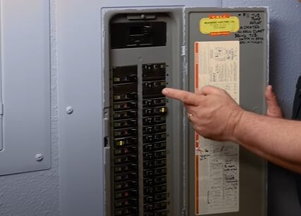 A man is pointing at a circuit breaker box