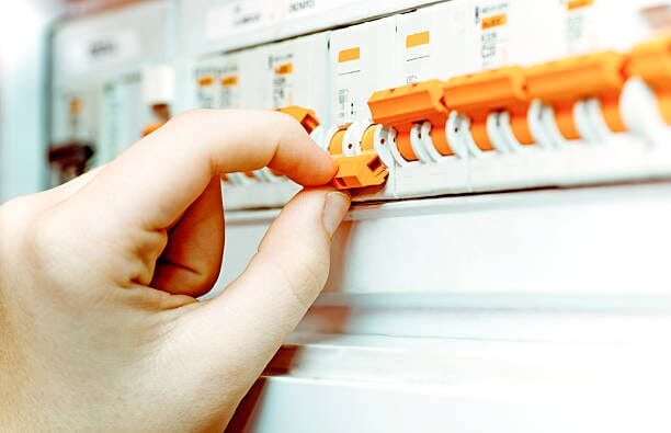 A person is turning off a circuit breaker in an electrical panel