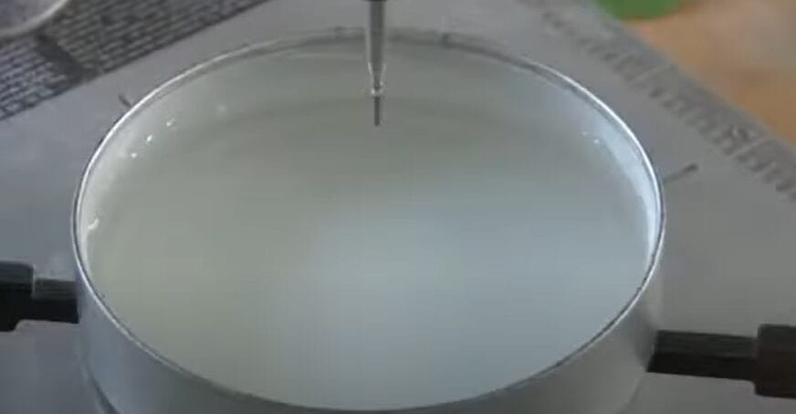 A white liquid is being poured into a metal container