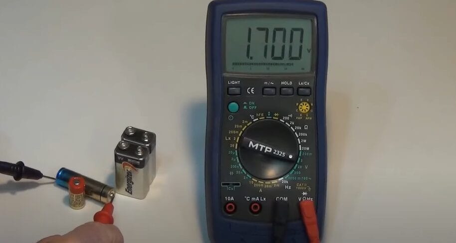 An individual demonstrates how to measure DC voltage using a multimeter