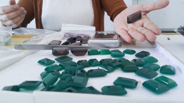 A woman is cutting green gemstones