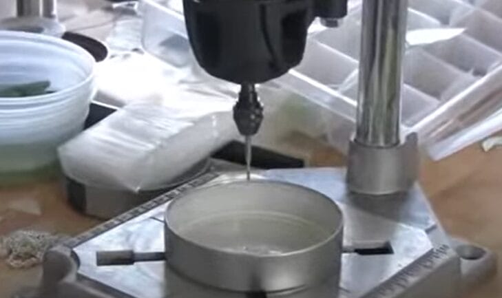 A machine is being used to drill the bottom of a water cup