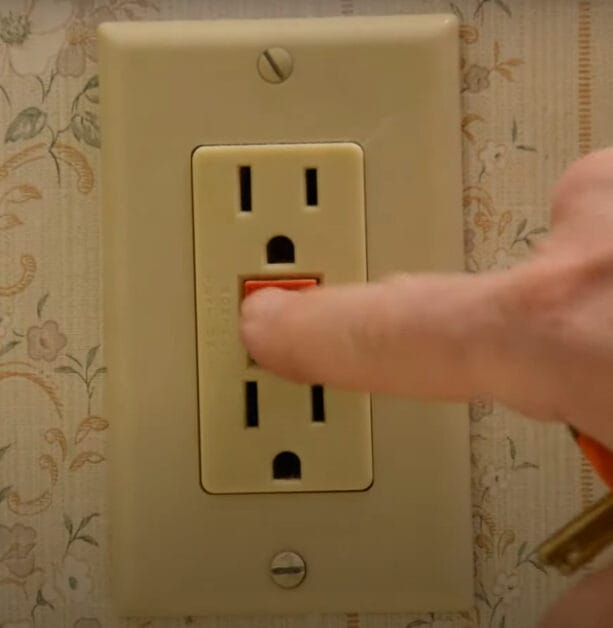 A person is turning on the GFCI outlet
