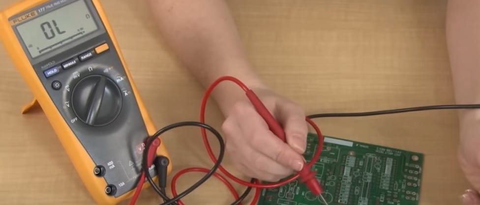 A person is using a multimeter on a circuit board
