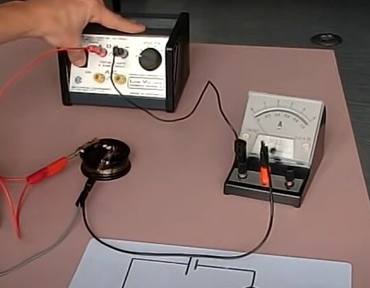 A person is using a voltage meter on a table to measure electric current